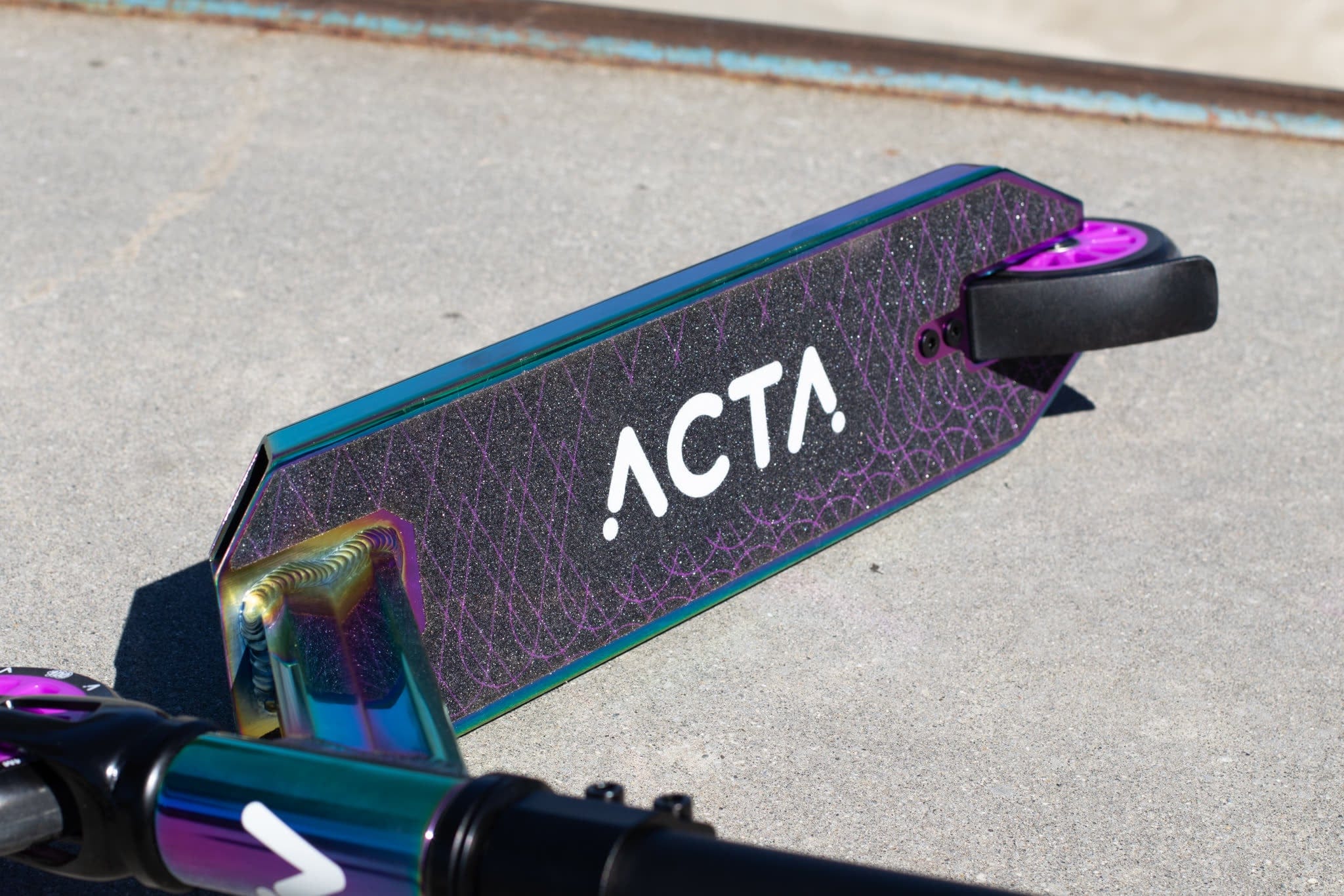 Deck de trottinette freestyle ACTA Neochrome irisé, gros plan avec roue noire