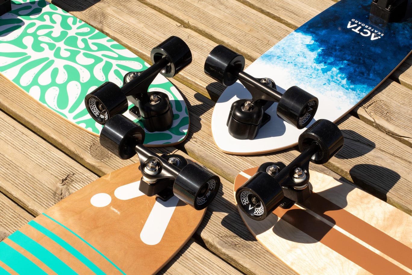 Surfskates ACTA aux decks colorés alignés en extérieur, trucks avant visibles